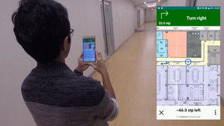 A picture of the author walking through a corridor while holding up a phone. The phone is showing a map of the area with navigation instructions.